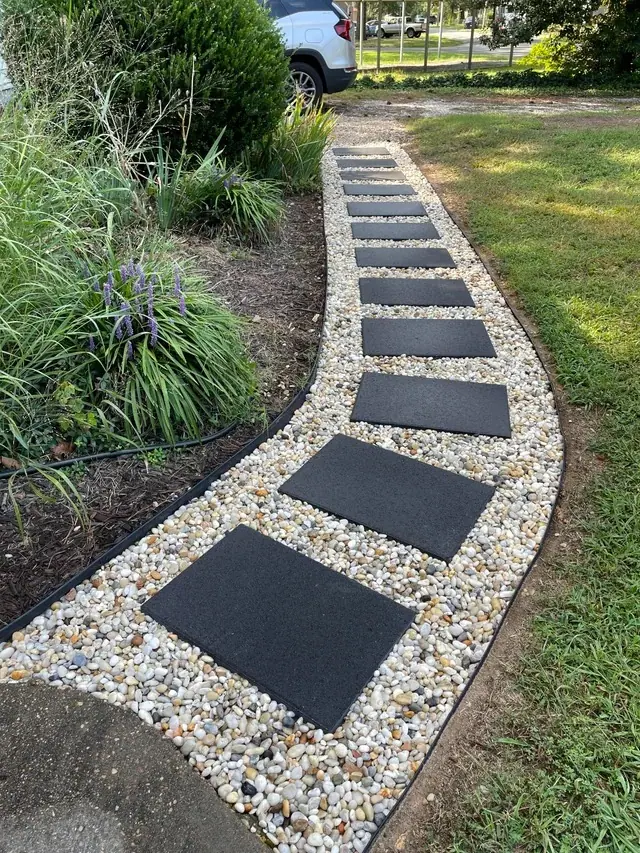 A gravel path with black stepping stones beside plants